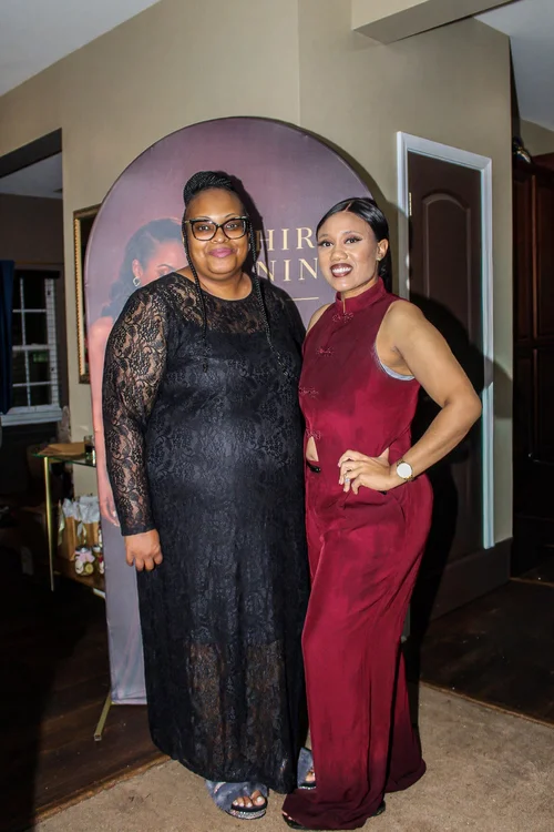 Two guests posing beside the birthday backdrop