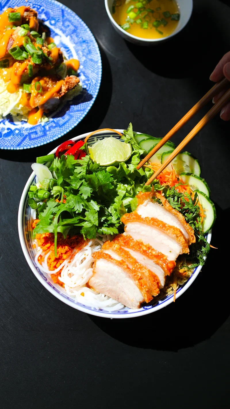 Crispy pork bò bún with fresh herbs and pickles, served at the restaurant