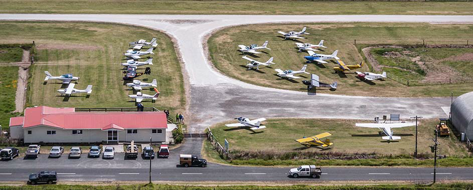 Aerial view of Dargaville Aero Club in Northland, New Zealand, showing light aircraft parked near the clubhouse and taxiway, with runway and surrounding facilities visible.