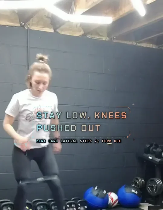Coach Tabitha doing mini band lateral steps, mini band above her knees, start: quarter squat, band tight