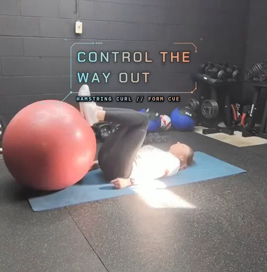 Coach Tabitha lying on a mat with her heels on a stability ball, hips lifted, curl in, control out