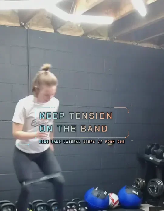 Coach Tabitha doing mini band lateral steps, mini band above her knees, step back in, keep tension