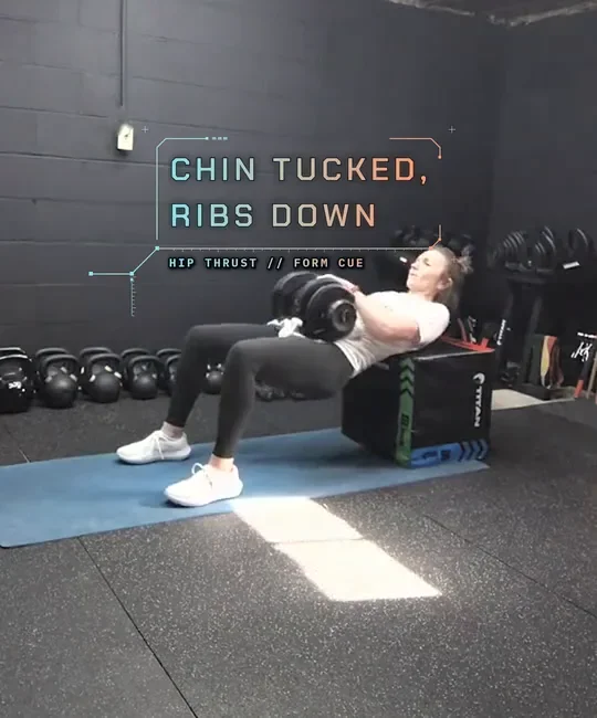 Coach Tabitha doing a dumbbell hip thrust with her upper back on a plyo box, drive up