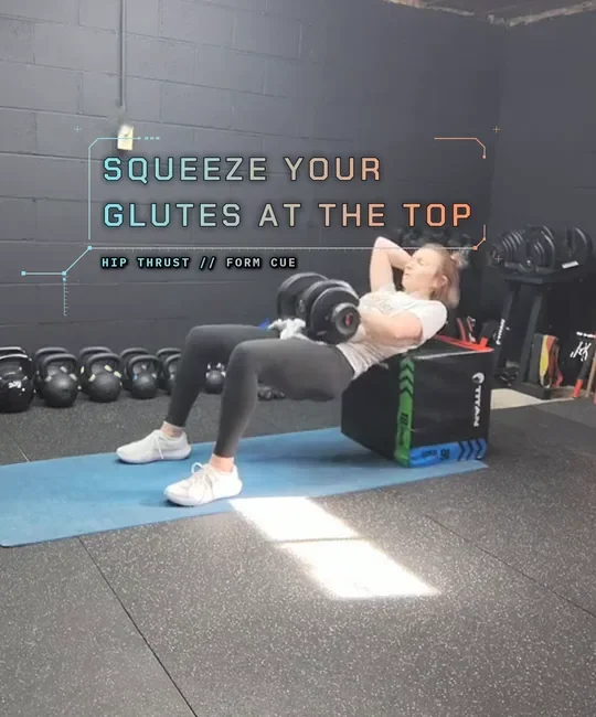 Coach Tabitha doing a dumbbell hip thrust with her upper back on a plyo box, top: squeeze, body flat