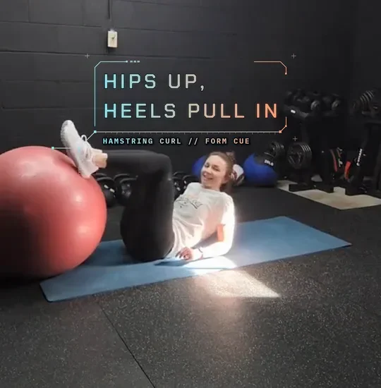 Coach Tabitha lying on a mat with her heels on a stability ball, hips lifted, setup: heels on the ball
