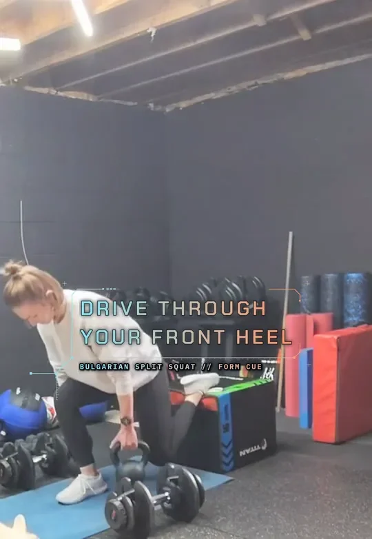 Coach Tabitha in a Bulgarian split squat with her rear foot on a plyo box, holding kettlebells, drive up through the front heel