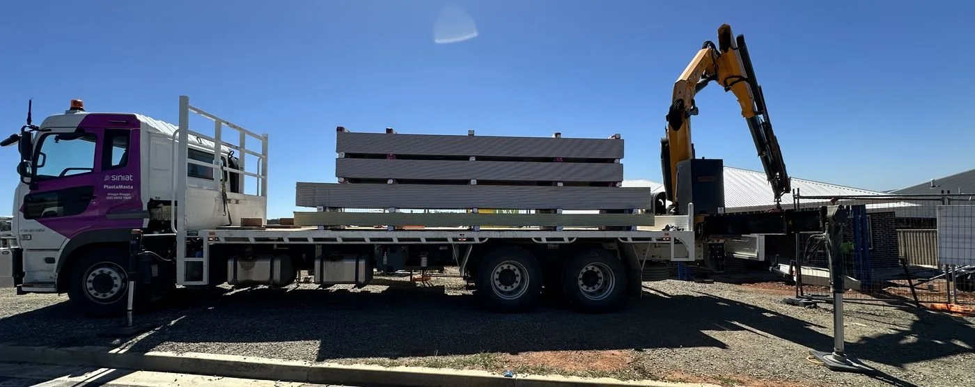 PlastaMasta Wagga crane truck delivering plasterboard to a new home site