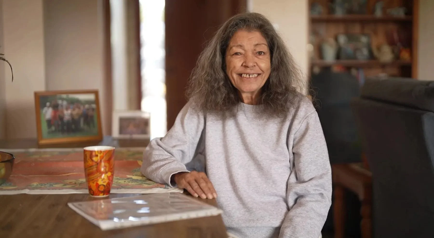 A smiling woman seated at her dining table