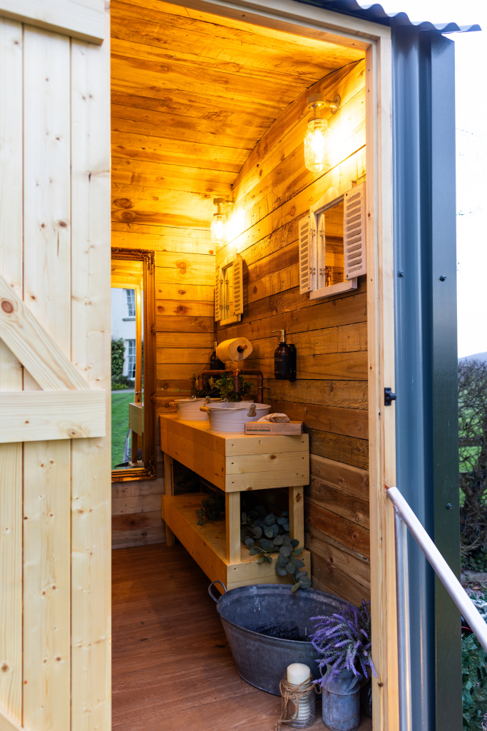 Nomadic Washrooms timber-lined washroom with Henley Naturals care beside the basin