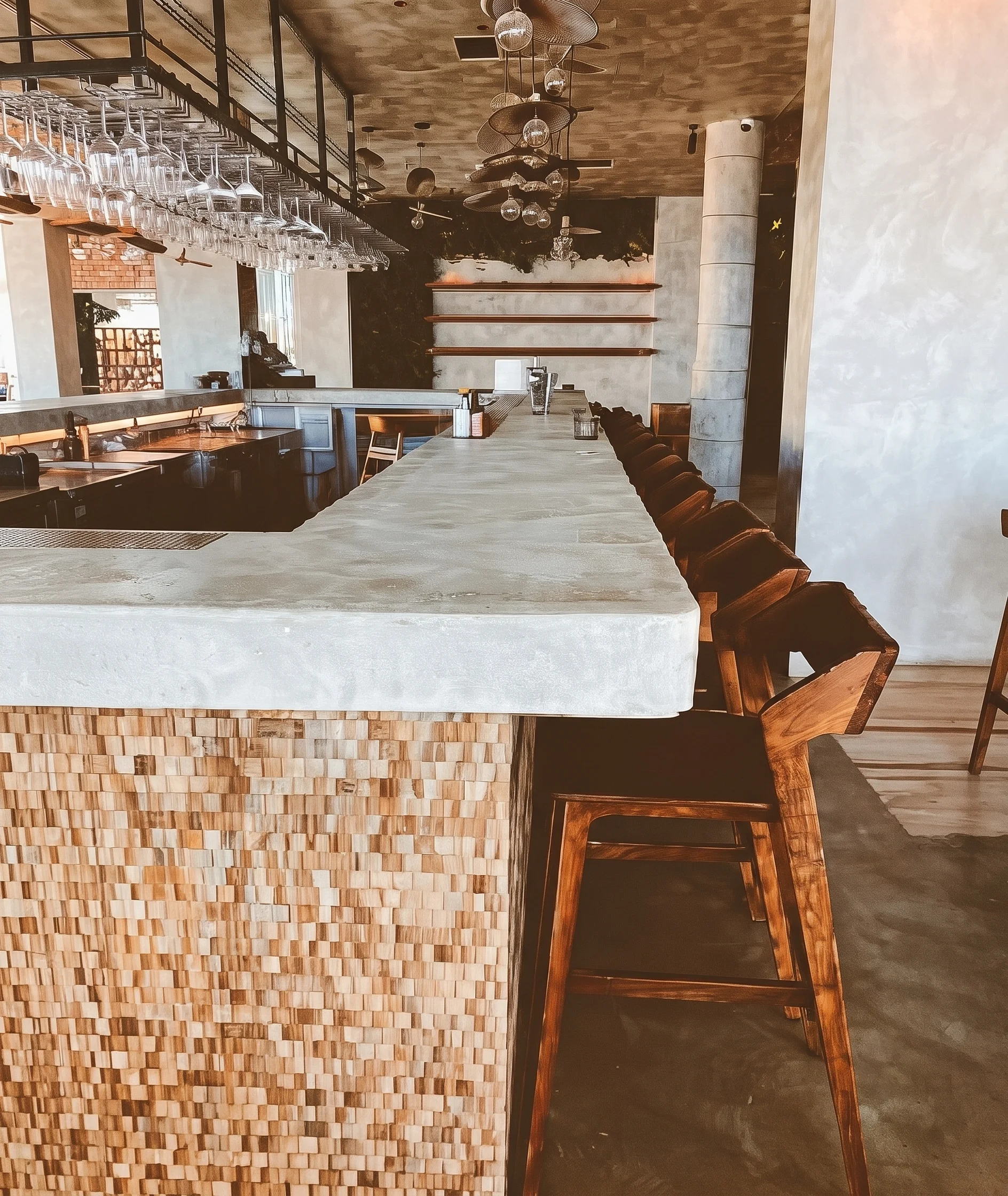 Row of wooden bar stools along a stone countertop