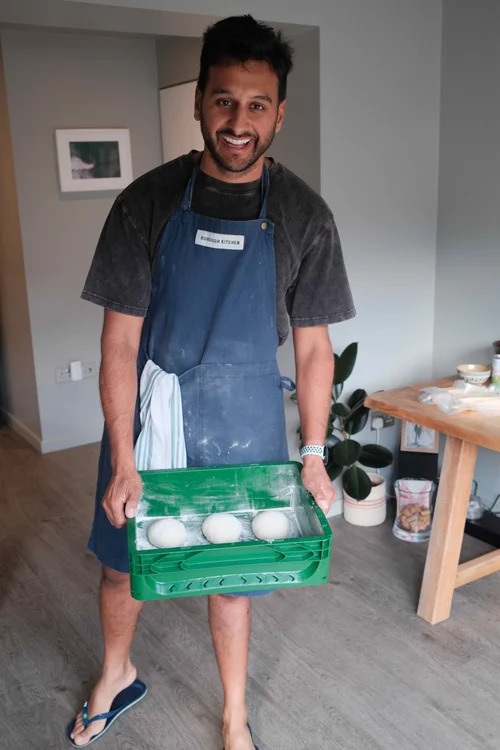 Zaeem holding a tray of pizza dough balls