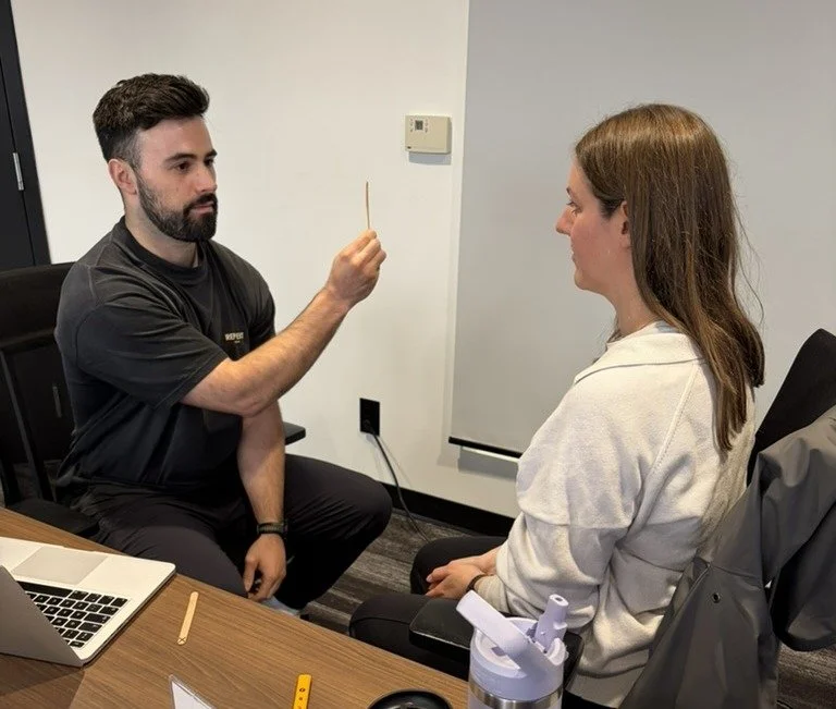 Clinician holding a target to assess a colleague’s eye movements