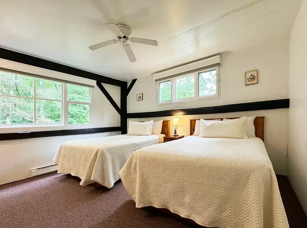 Apartment 23 bedroom with two full beds, ceiling fan, and framed wall art