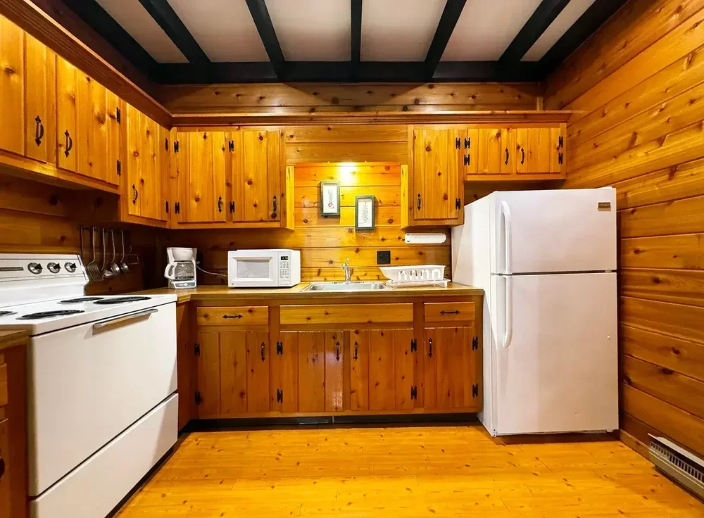 Apartment 23 full kitchen with pine cabinetry, white appliances, and open shelving