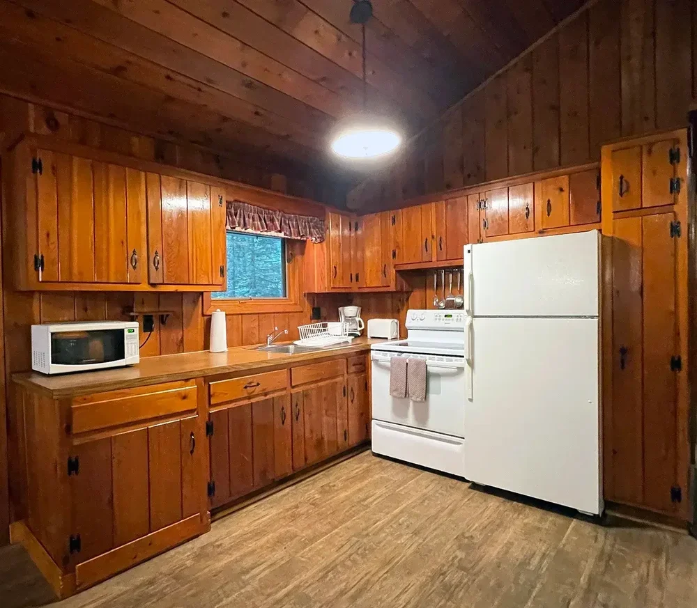 Cabin 36 full kitchen with wood cabinets, refrigerator, and stove