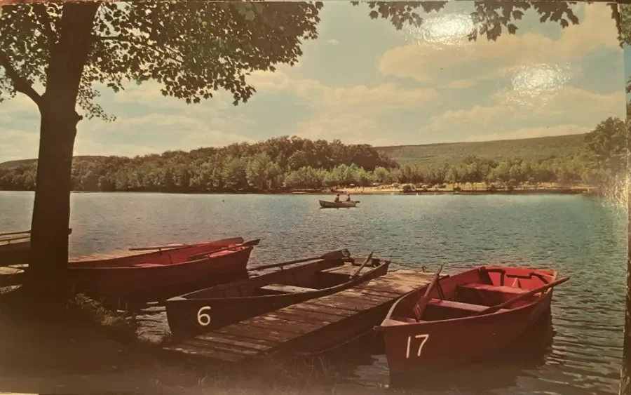 Vintage color photograph of numbered rowboats at a dock on Mountain Springs Lake with wooded Pocono hills beyond the lake
