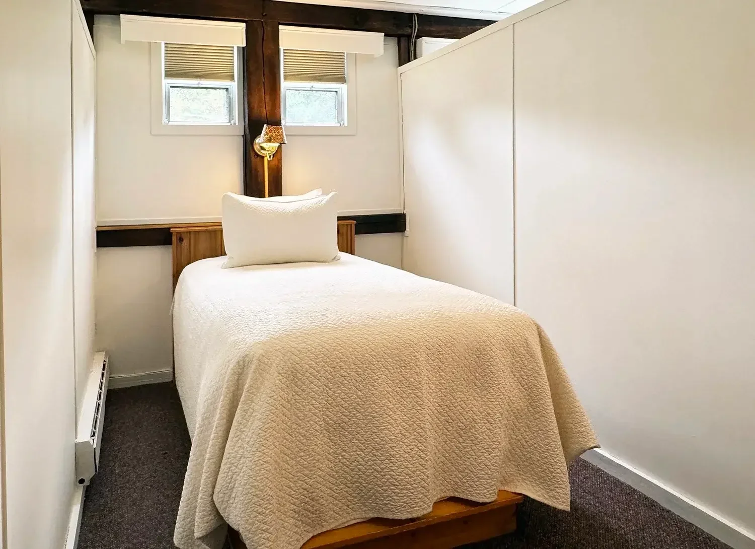 Apartment 22 second bedroom with twin bed, sconce light, and wood beams