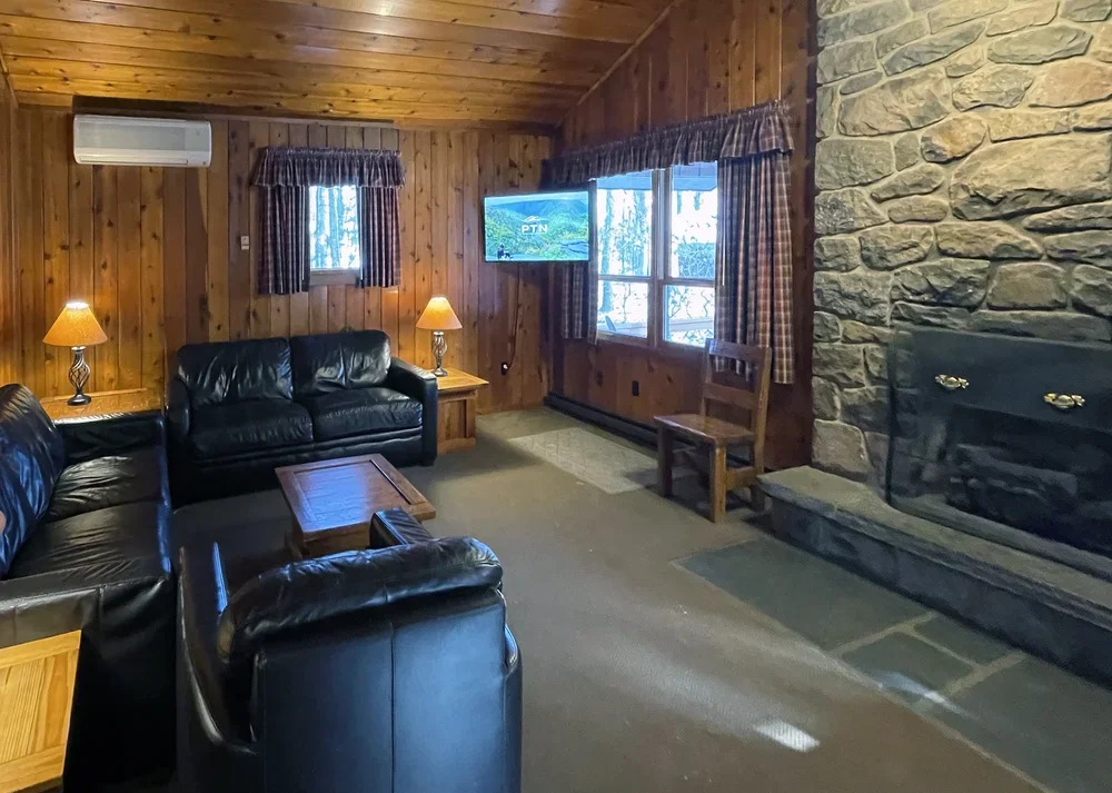 Cabin 36 living room with stone fireplace, leather seating, and Smart TV