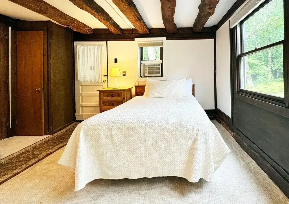 Apartment 21 full bed with wood-beam ceiling and window air conditioner