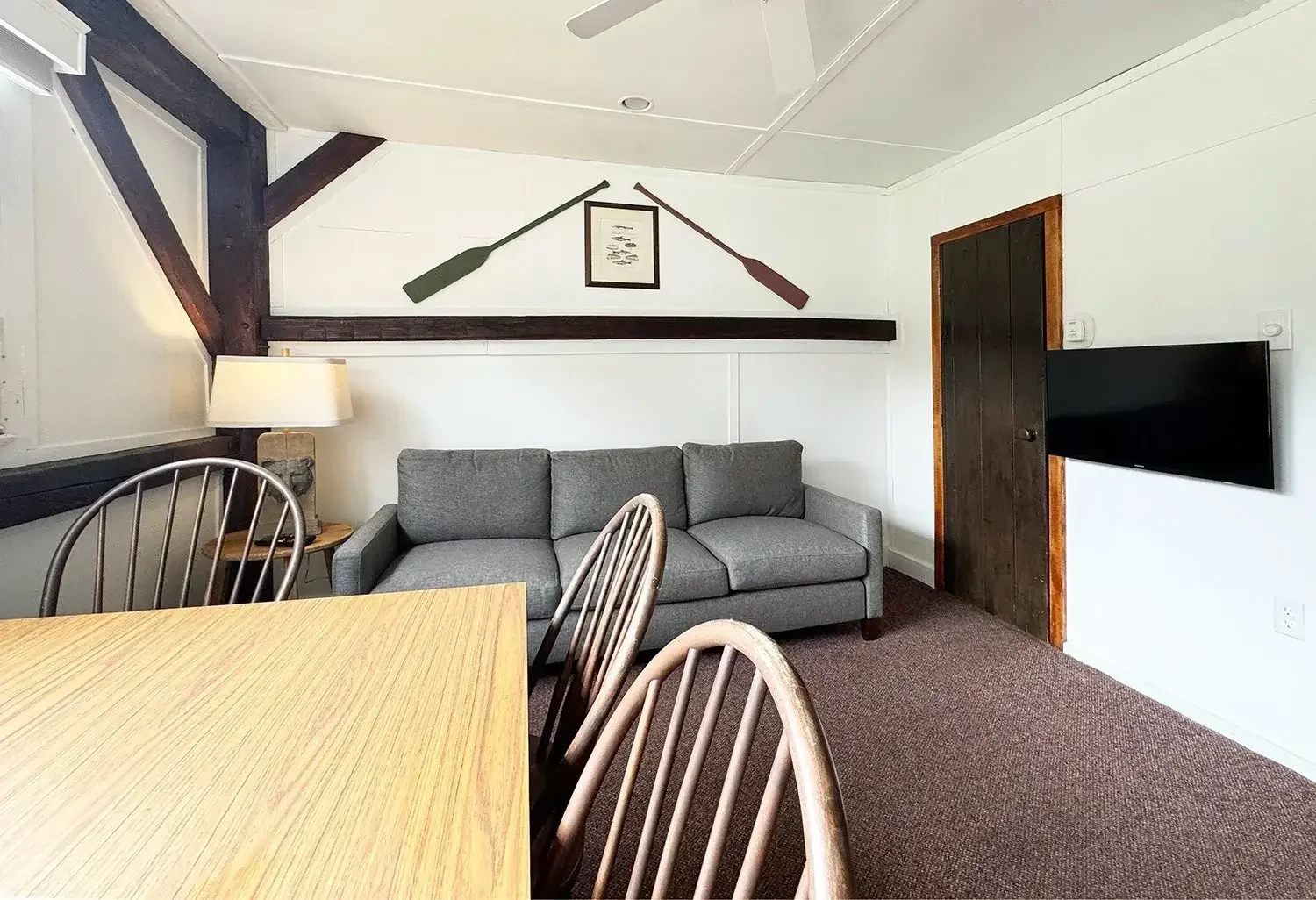 Apartment 22 living room with gray sofa, dining table, and decorative oars