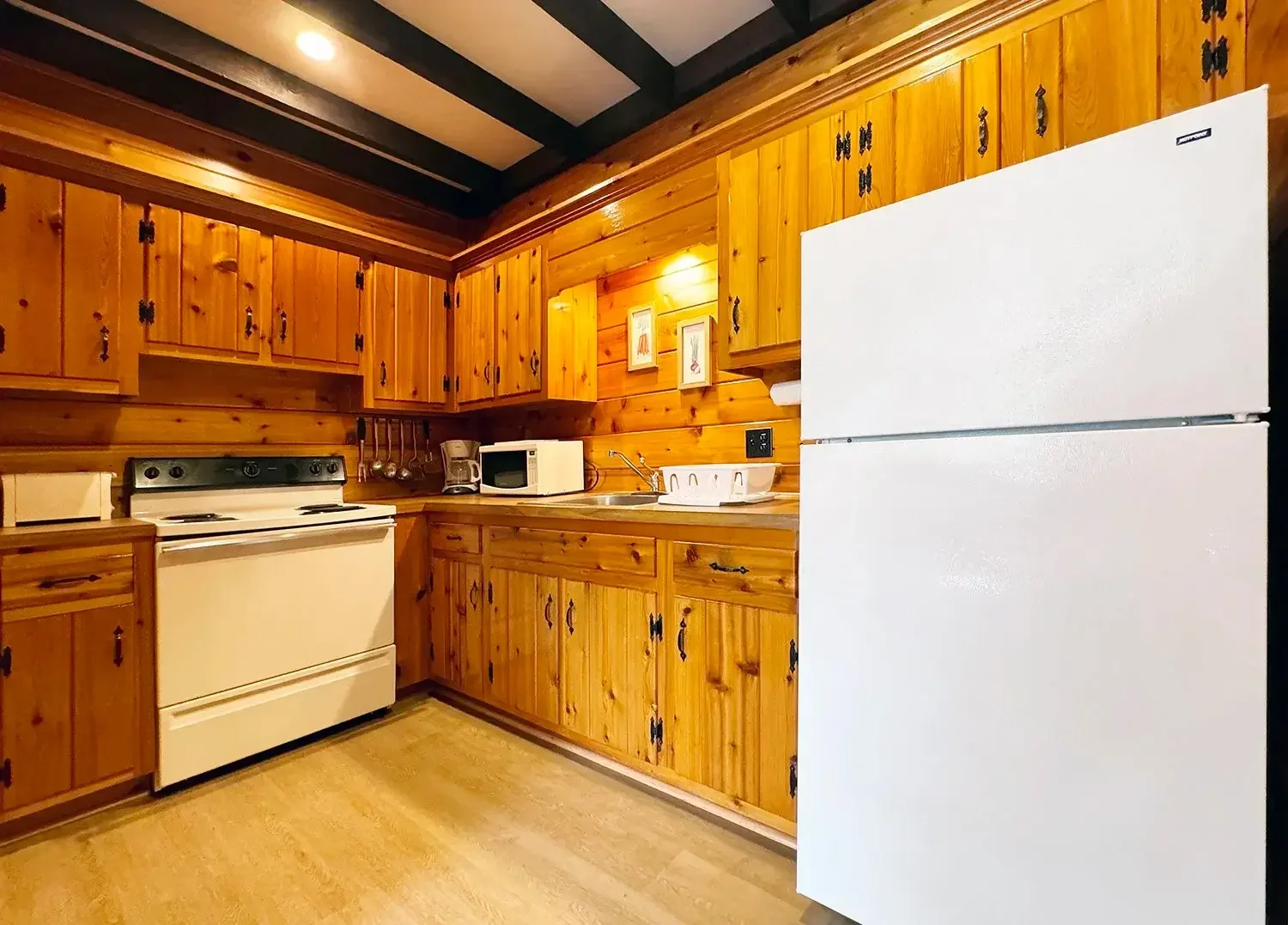 Apartment 22 full kitchen with pine cabinetry, white appliances, and modern lighting