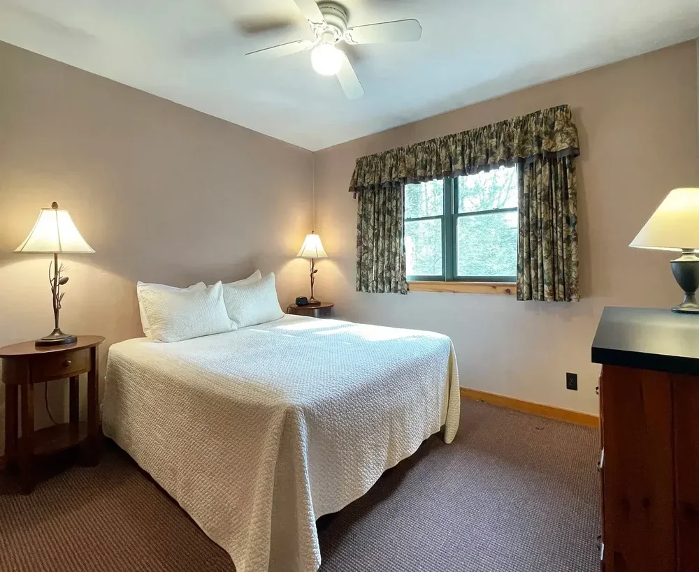 Cabin 42 queen bedroom with warm lighting and large window