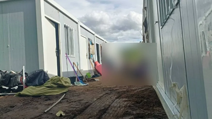 Prefabricated grey units in a row; people blurred