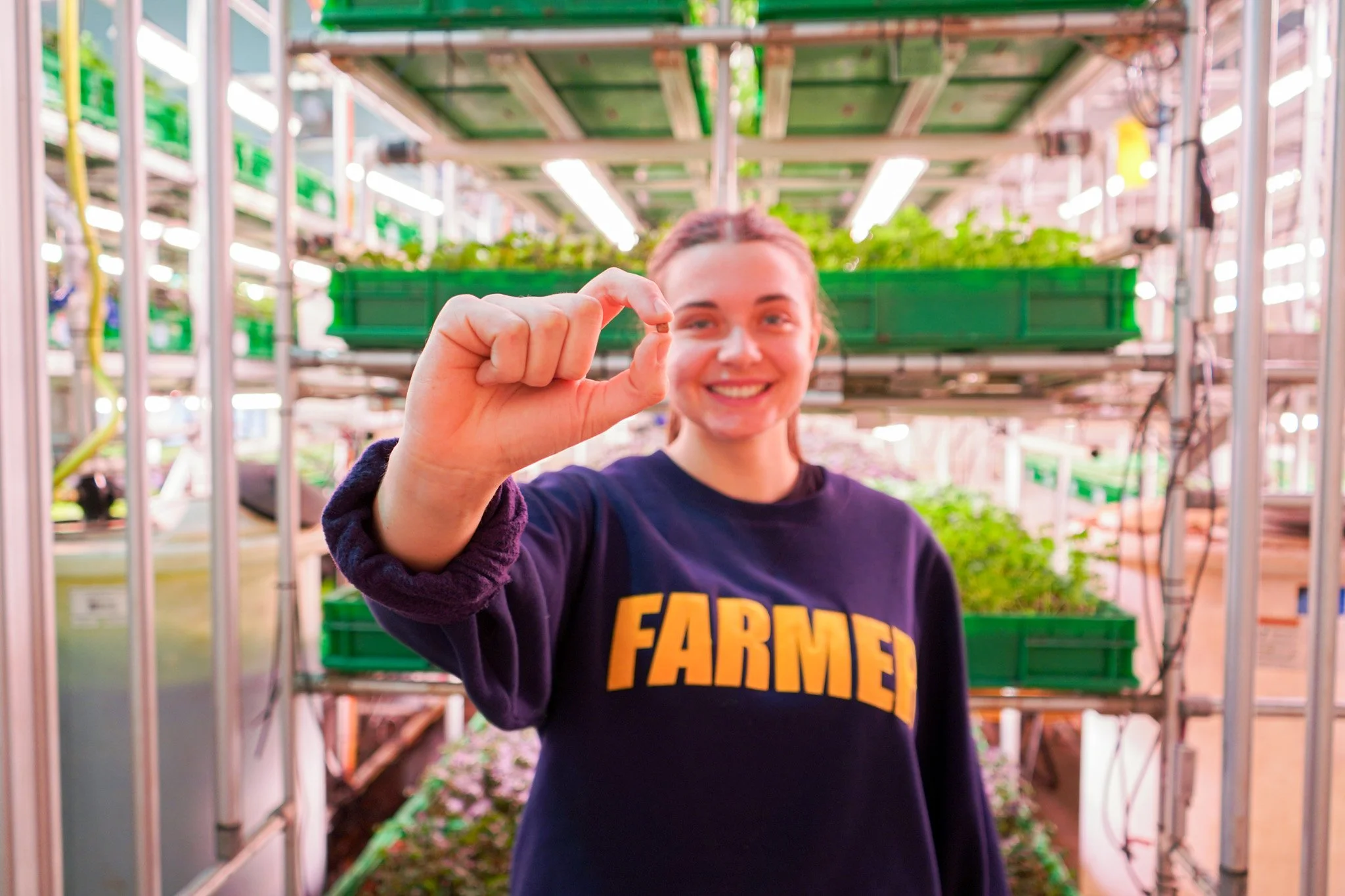 Farmer Lexa holding a single seed inside the Arlington farm
