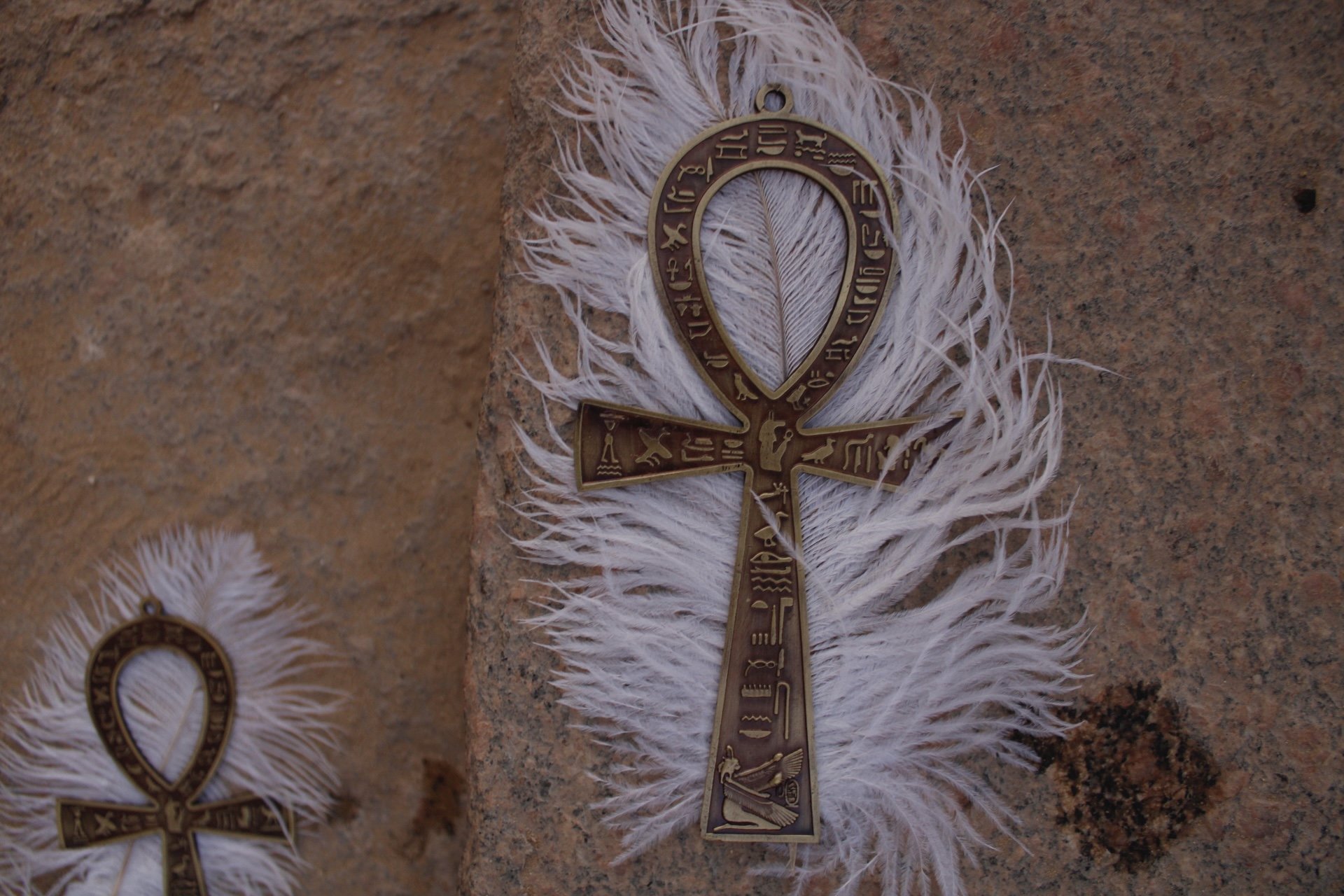 Feathered ankh ritual objects resting on stone