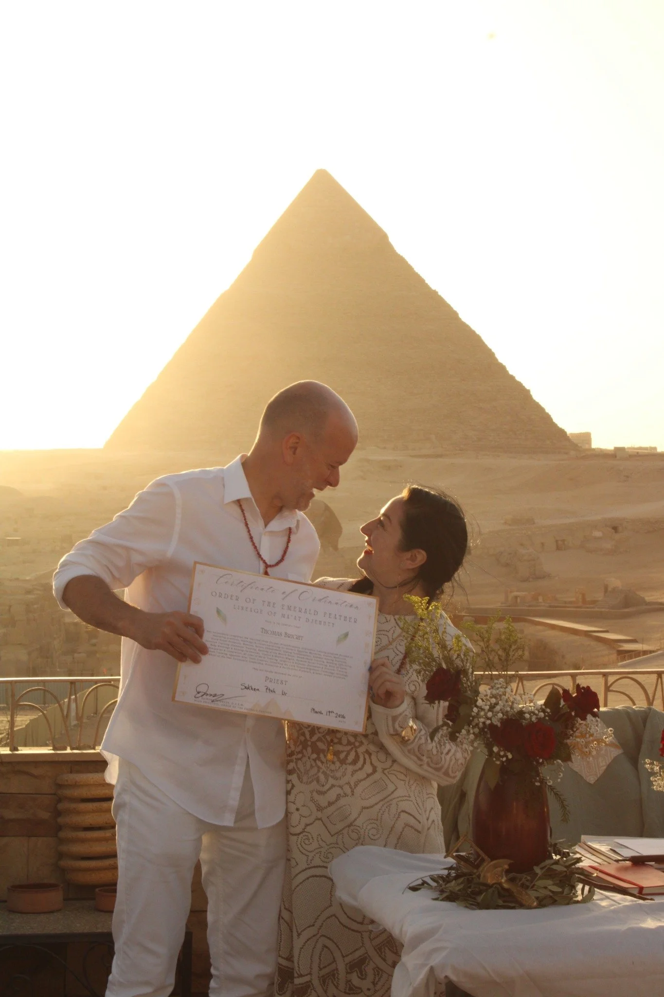 An ordination ceremony before the Great Pyramid, with a certificate and flowers