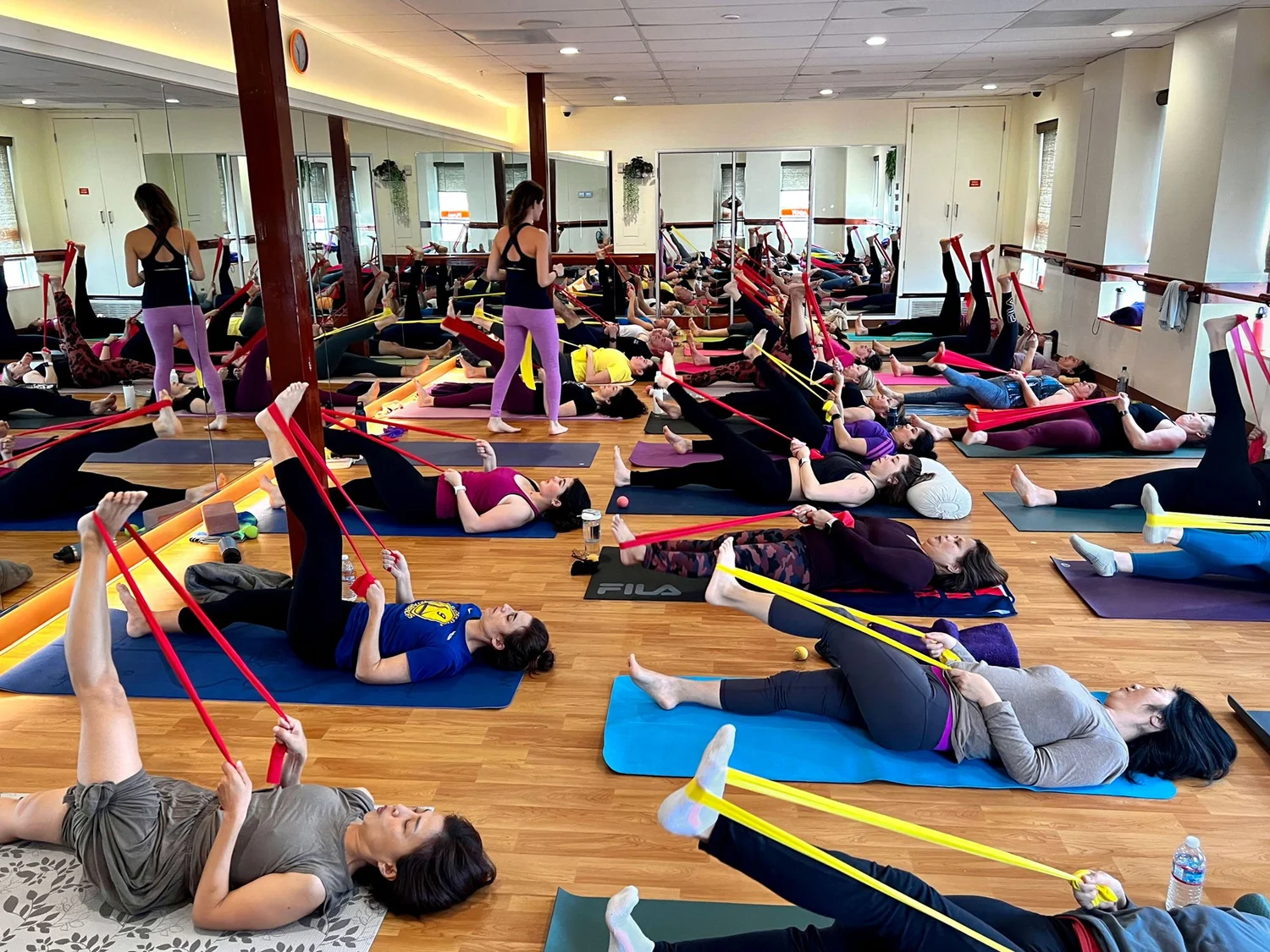 Yogalates class working with resistance bands on their mats