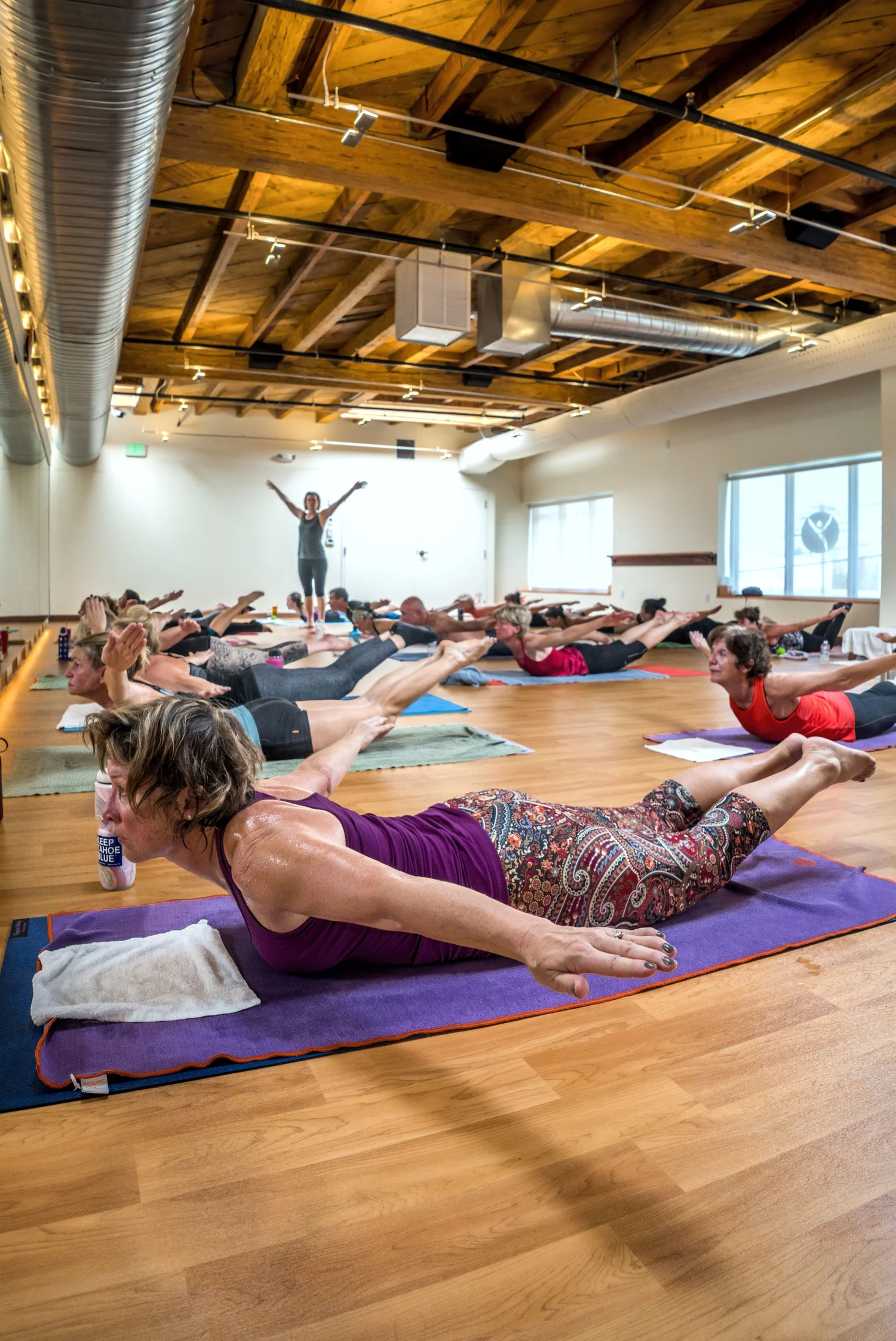Regina leading a HOT26+ class in the hot room at Yoga Health Center, arms raised