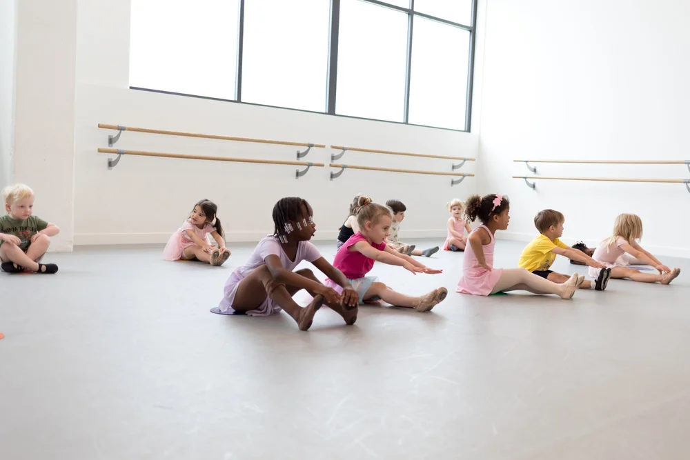 Little dancers sitting in a circle on the studio floor