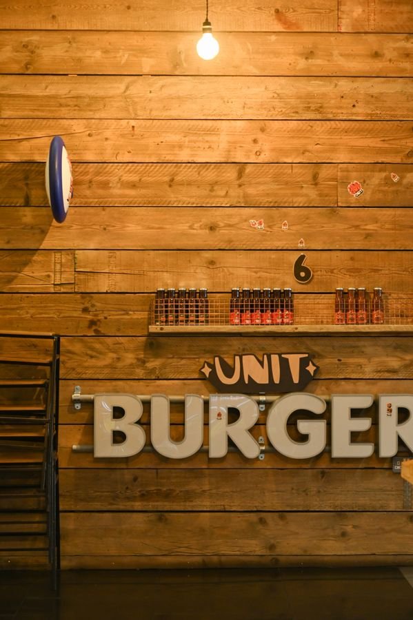 The UNIT BURGER sign and house sauces on the wooden wall at Headford Street
