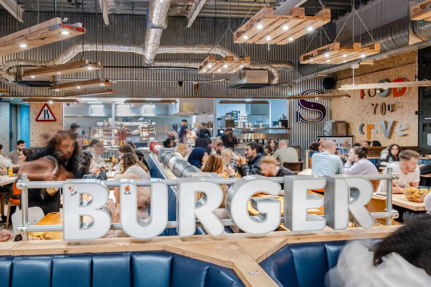 The BURGER sign above the booths, with the open kitchen behind, at Unit Valley Centertainment