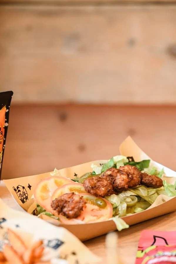 A fresh salad with crispy chicken, tomato, pickles and jalapeños