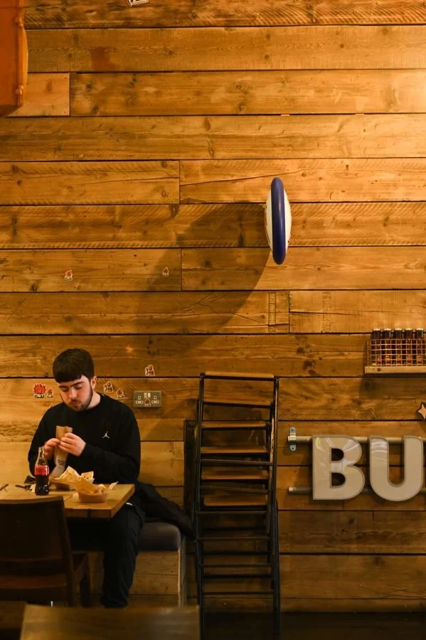 A diner unwrapping a burger in a booth at Unit Headford Street