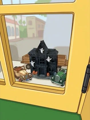 Black haunted house with three ghosts sitting in a train window between two toy cars