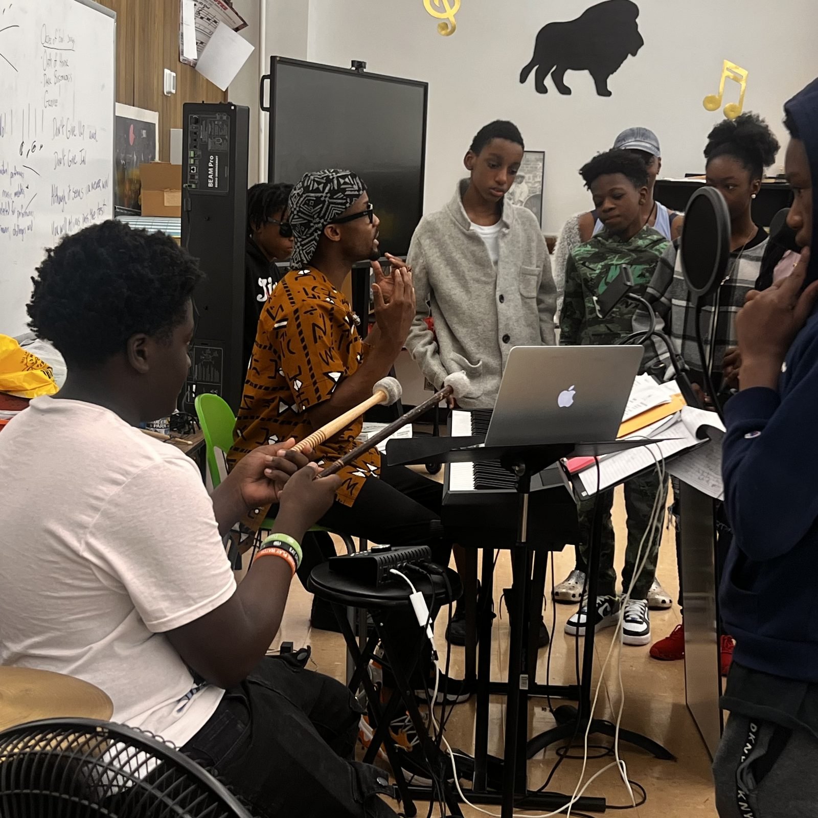 Students gathered around a keyboard and laptop during a songwriting session