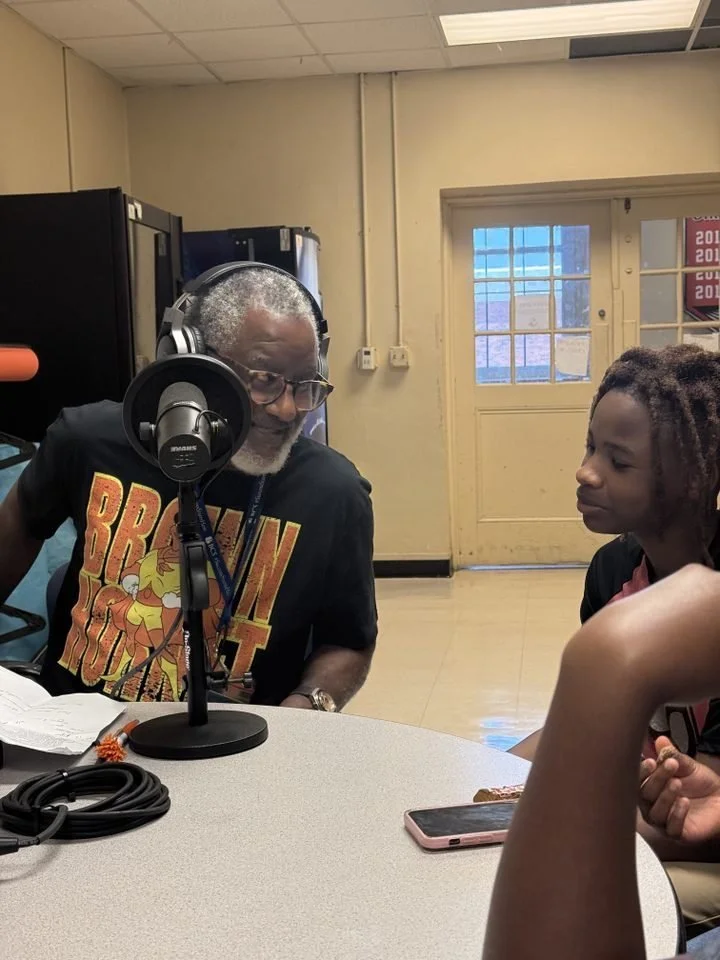 A student recording at a microphone alongside a teaching artist