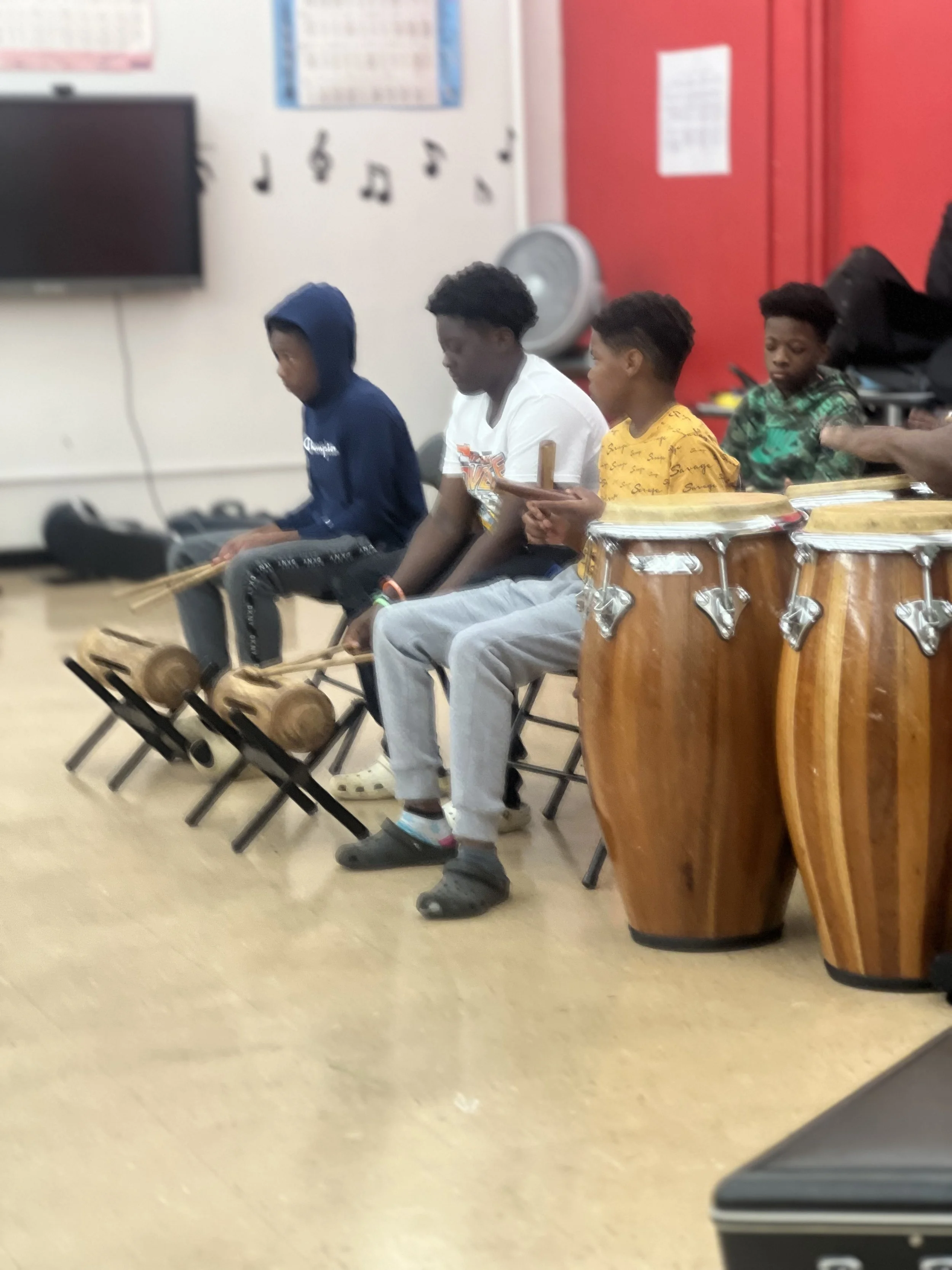 Students playing congas and hand percussion in the band room