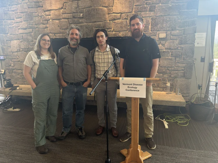 Renee, a blonde woman wearing a whiteUMass lab coat, has her hand in a centrofuge.