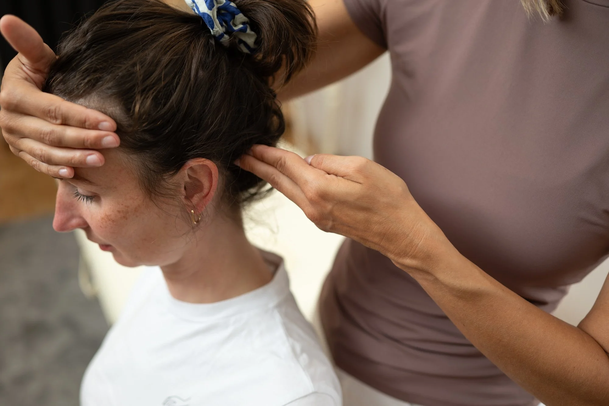 Osteopressur im Nackenbereich: Susanne behandelt eine sitzende Frau.