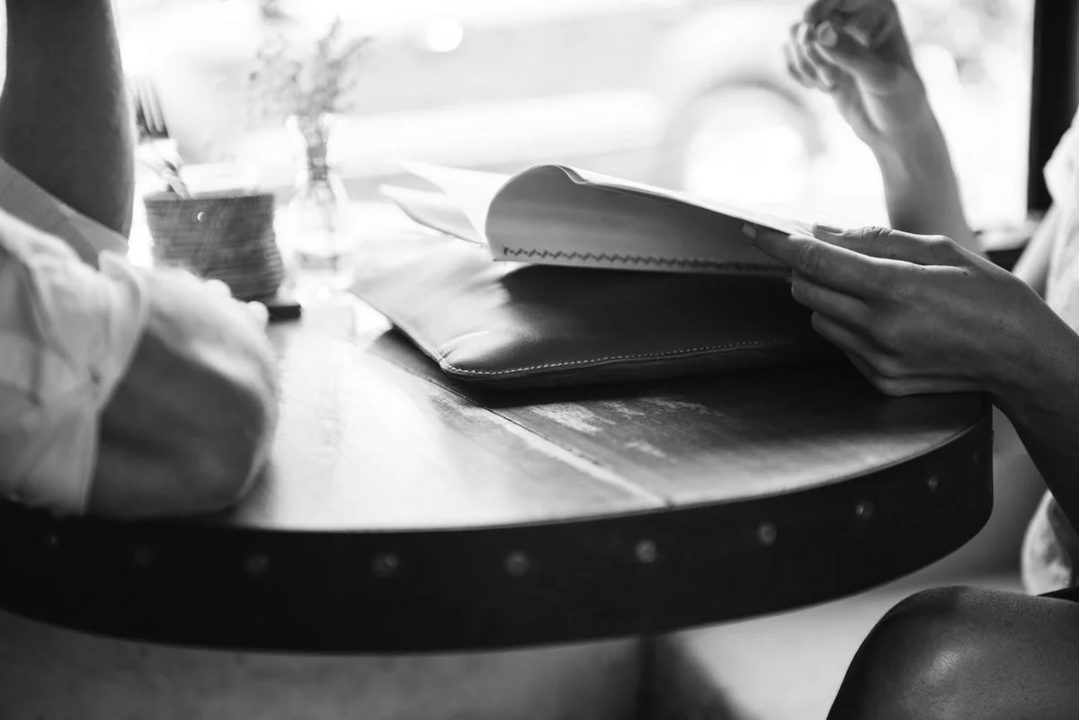 Black-and-white photo of two people talking across a cafe table