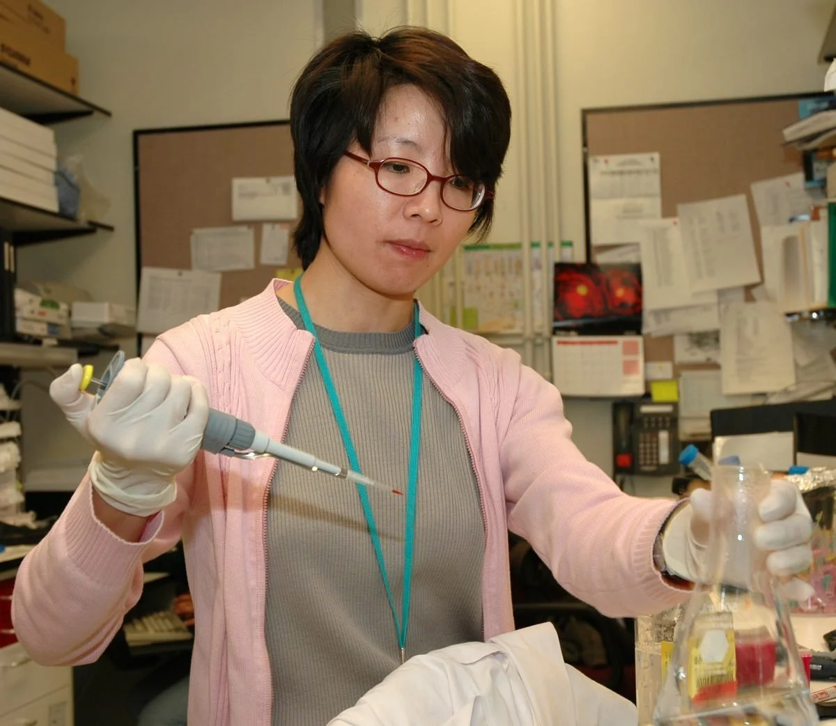 A scientist pipetting samples into a flask in a lab