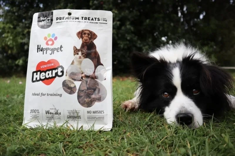 Border collie beside a bag of Happypet venison heart treats
