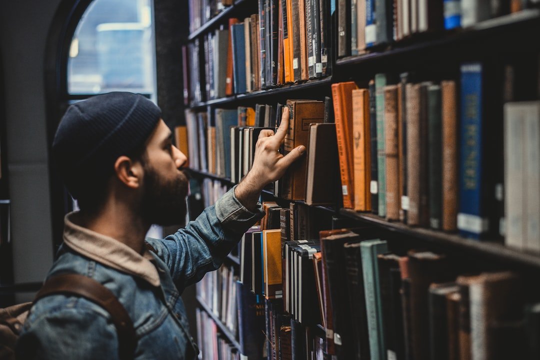man choosing a self-help book in a library