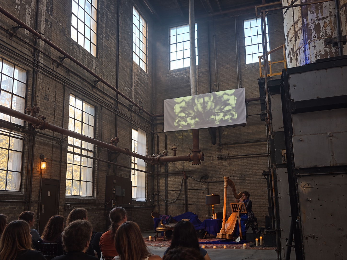A harpist performing in an industrial venue during Lora’s Racehorse ArtPrize 2025 event
