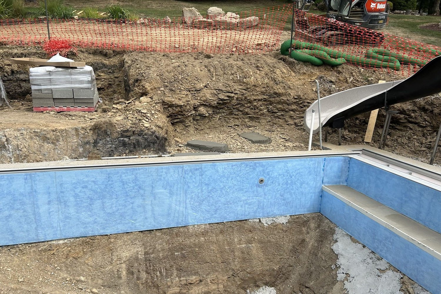 The pool floor and steps formed, with the slide in place on the bank
