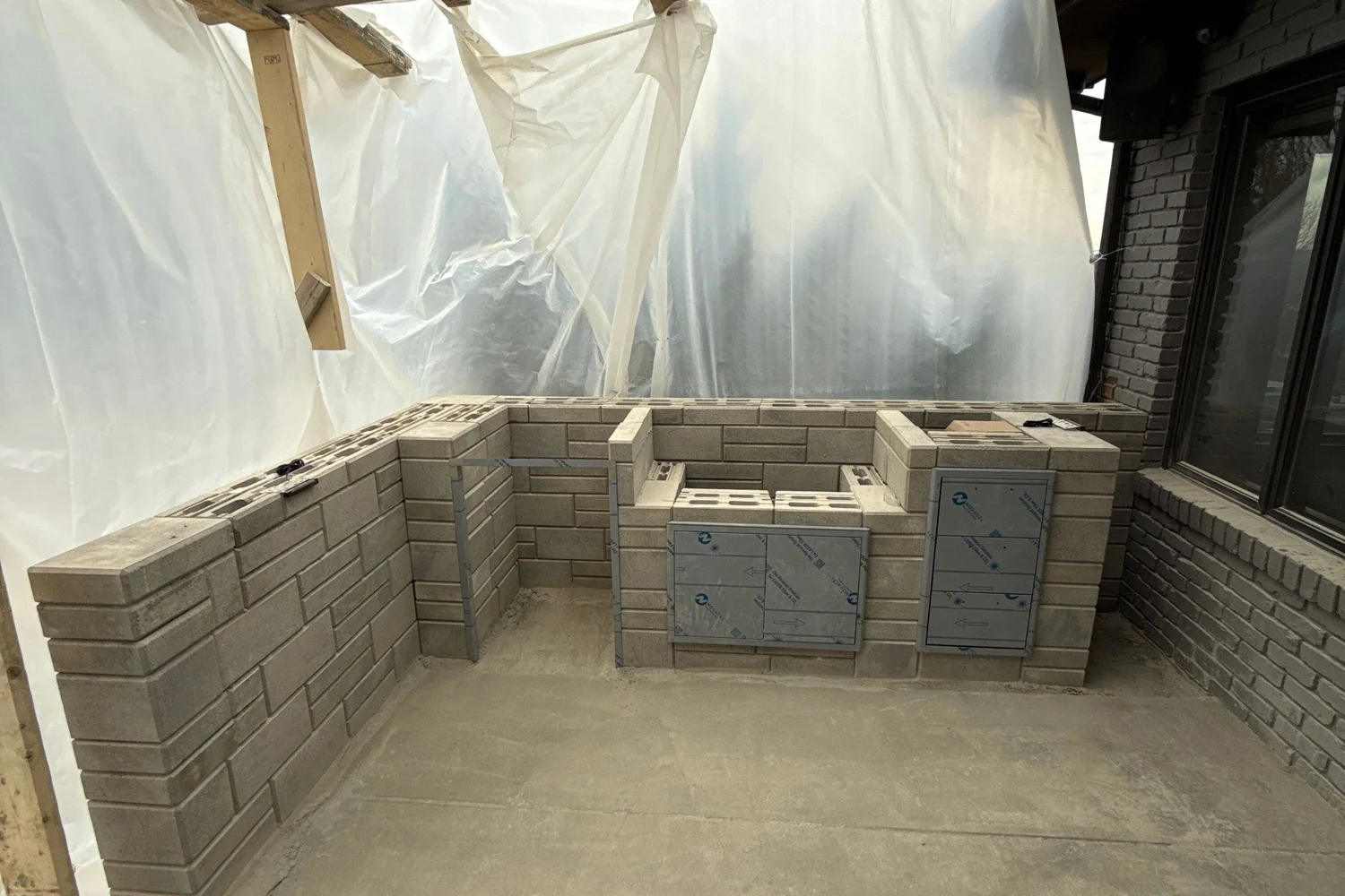 The outdoor kitchen's block frame under protective sheeting